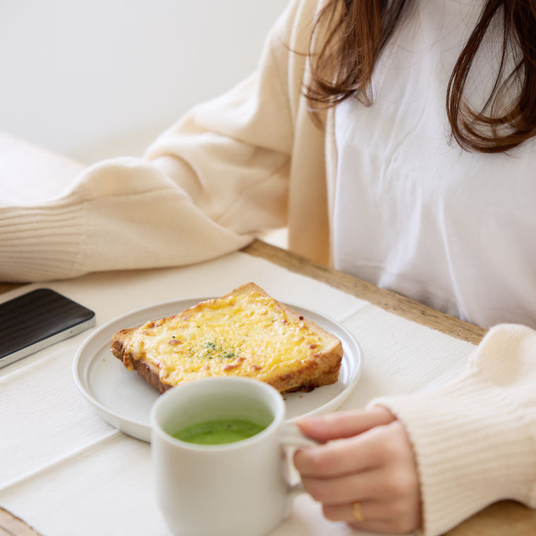 トーストを食べ抹茶を飲む女性