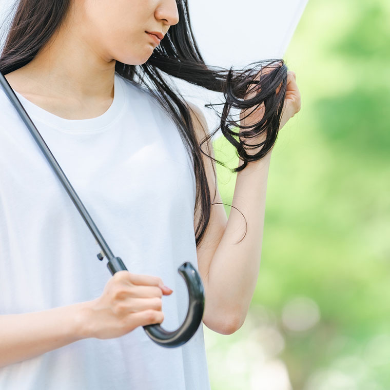 傘をさし、髪を気にする女性