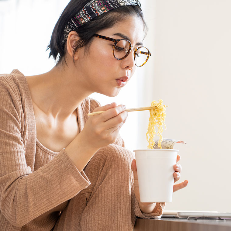 カップ麺を食べる女性