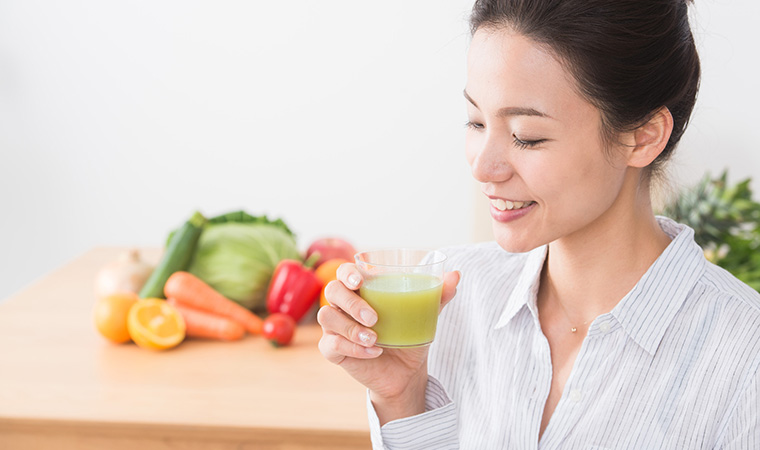 野菜ジュースを飲む女性と野菜