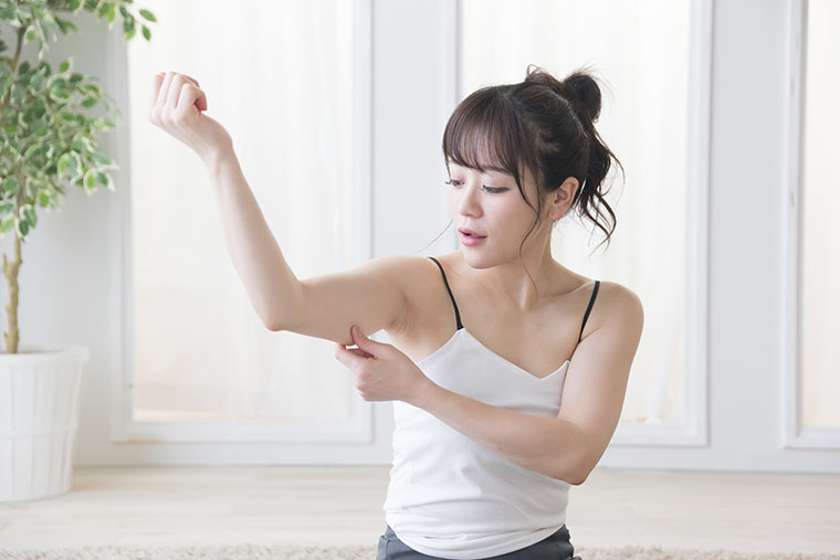 二の腕を触る女性