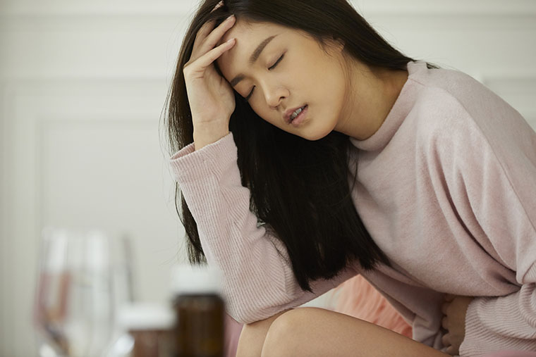 お腹を痛がる女性
