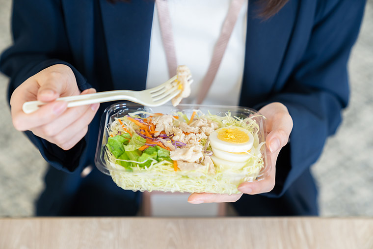 コンビニのサラダを食べる女性