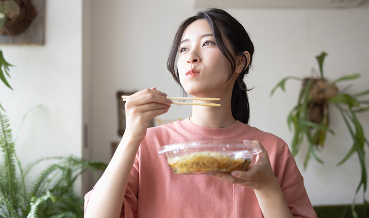 コンビニ食品を食べる女性
