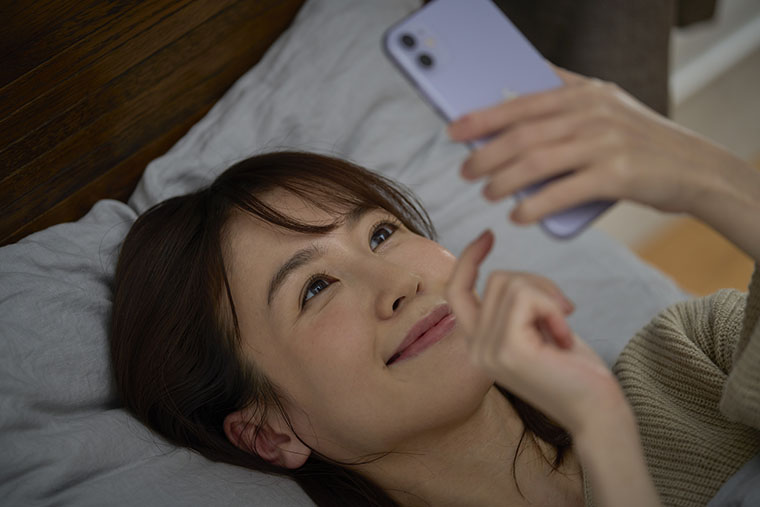 寝る前にスマホを見る女性