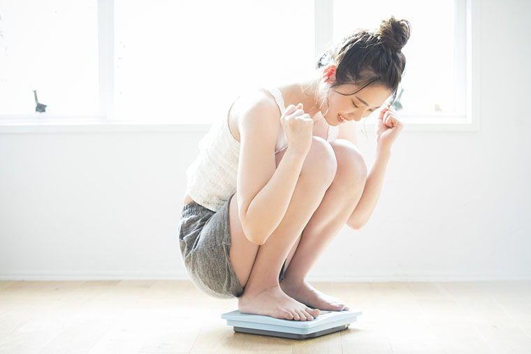 体重計に乗って喜ぶ女性