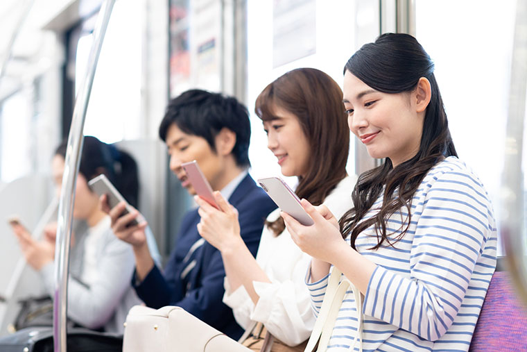 電車内でスマホを見る人たち