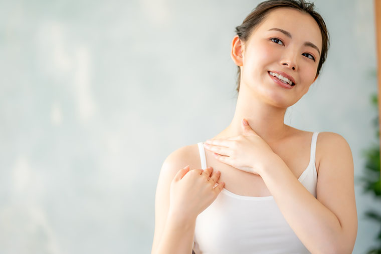 体に日焼け止めを塗る女性