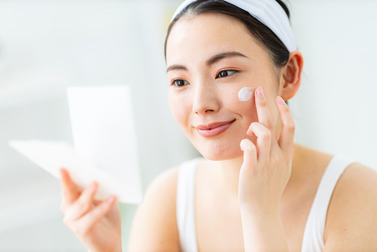 顔に日焼け止めを塗る女性