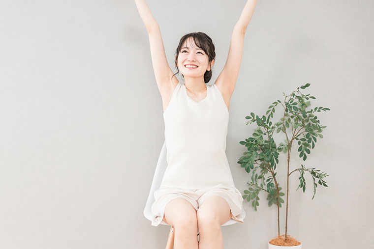 椅子に座って伸びをする女性
