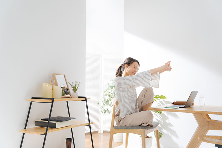 座りながら、体を伸ばす女性