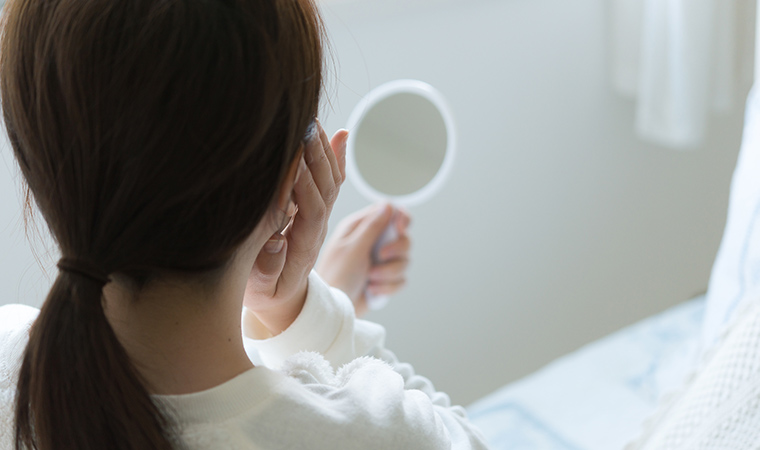 肌を鏡でみる女性