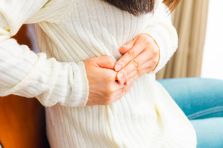 脇腹をおさえる女性