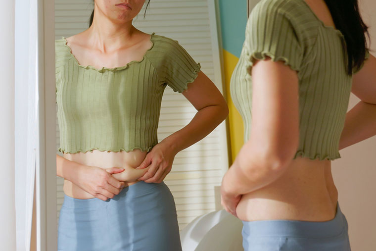 鏡を見てお腹をつまむ女性