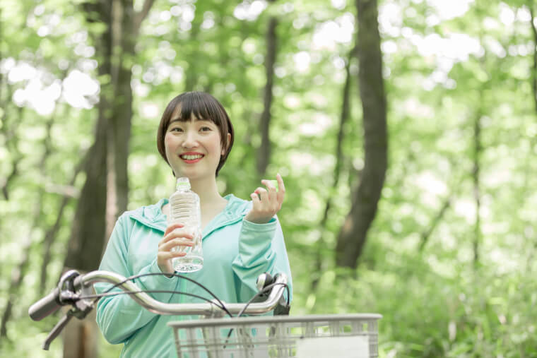 自転車を止めて水を飲む女性