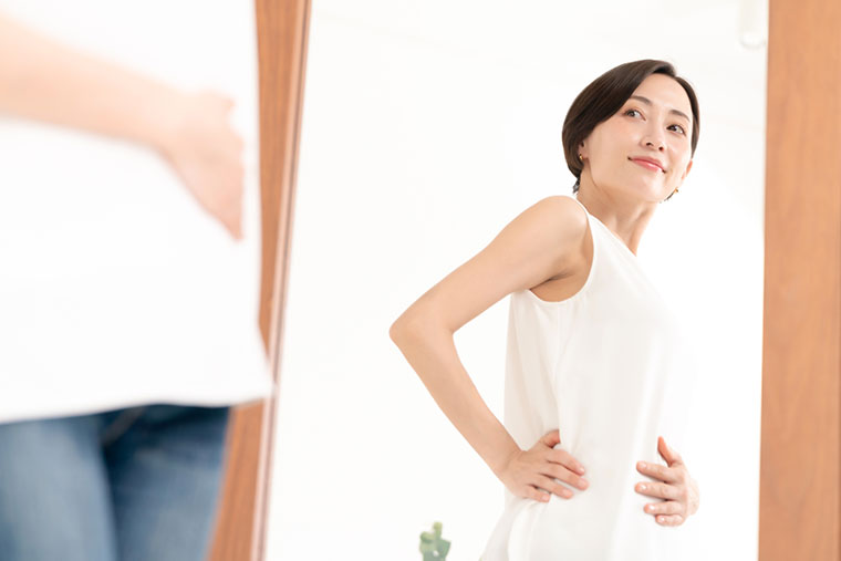 鏡で自分の体形をチェックする女性