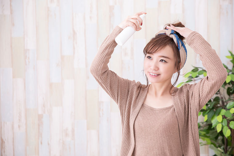 ヘアスプレーを使う女性