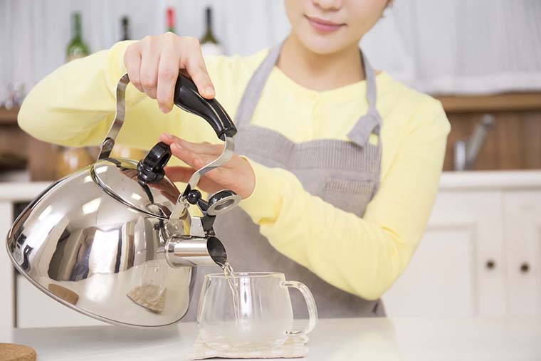 白湯をカップに注ぐ女性