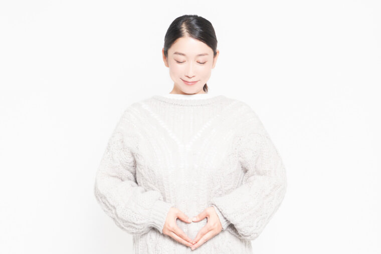 お腹の前でハートを作る女性