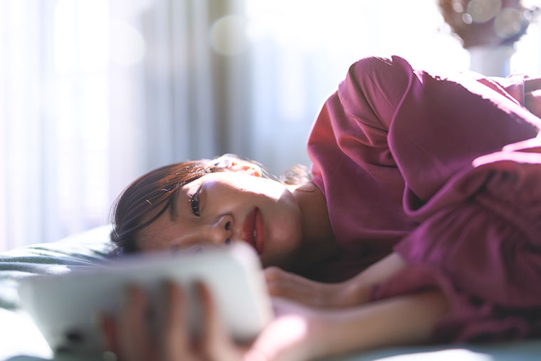 寝ながらスマホをみる女性