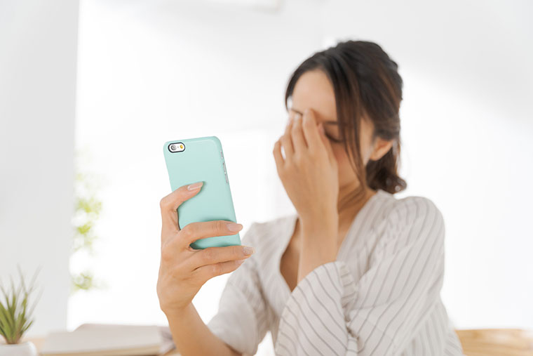 スマホを見て、目が疲れた女性