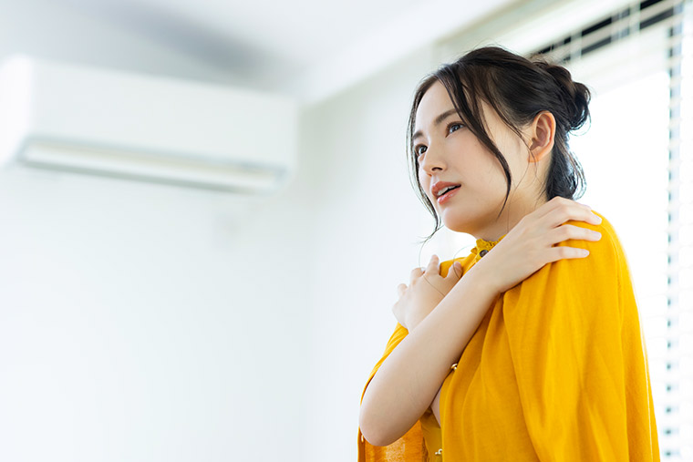 室内でクーラーの風で不調を感じる女性
