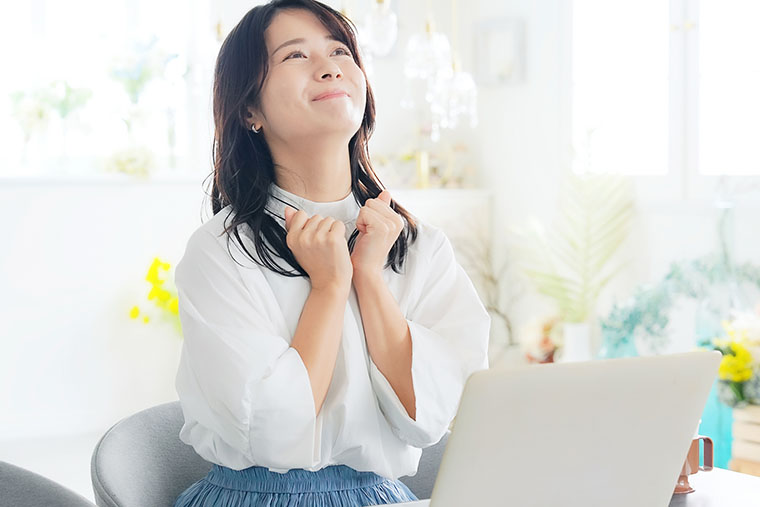 パソコンの前でガッツポーズする女性