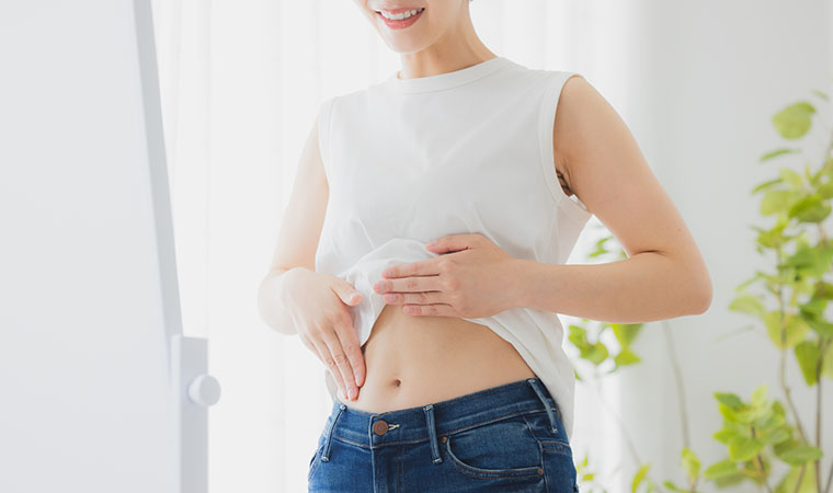 鏡でお腹をチェックする女性