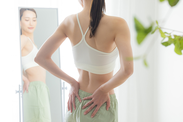 鏡で体型をチェックする女性