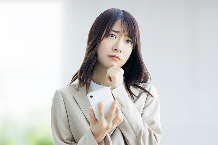 スマホを片手に悩む女性