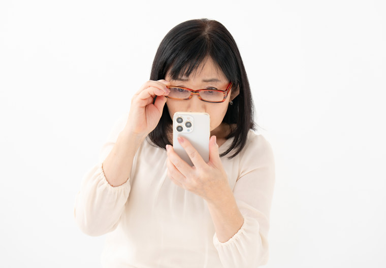 スマホを見ながら目が疲れている女性