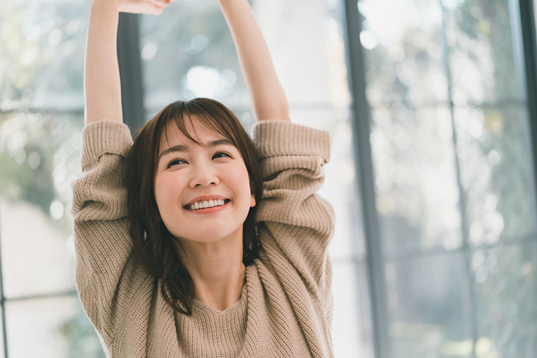 笑顔で伸びをする女性