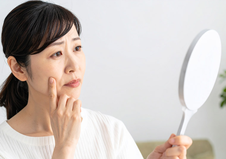 鏡を見ながら老け顔に悩む女性
