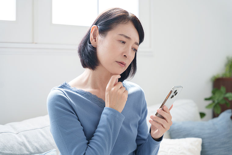 スマホを見て悩む女性