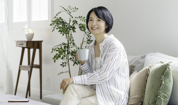 ソファに座って飲み物を飲む女性