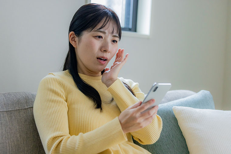 スマホを見てショックを受ける女性