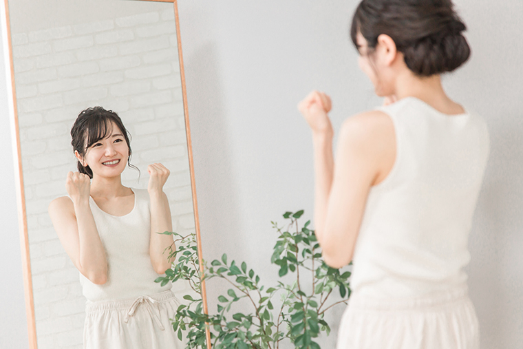 鏡を見てガッツポーズをする女性