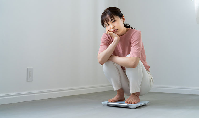 体重計に乗って悩む女性