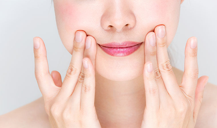 指で頬を上げる女性の口元