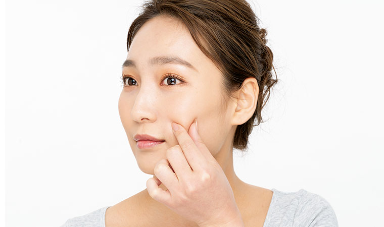 頬をつまむ女性