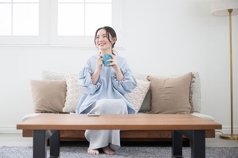 ソファに座って飲み物を飲む女性