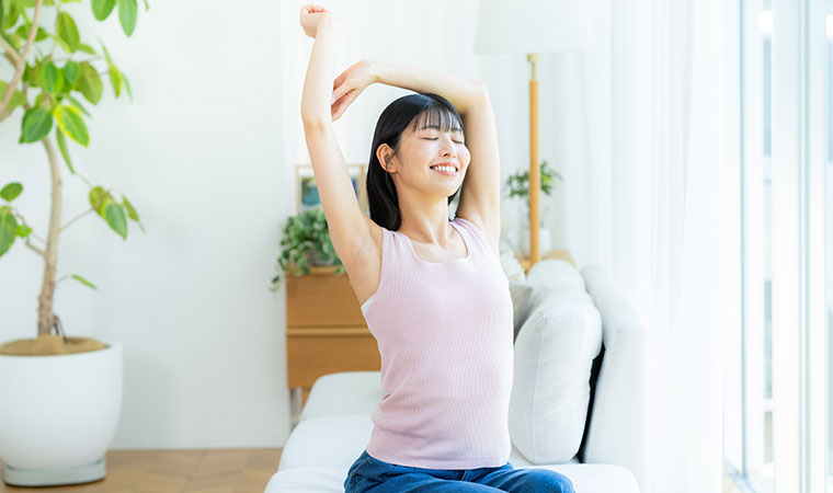 座って伸びをする女性