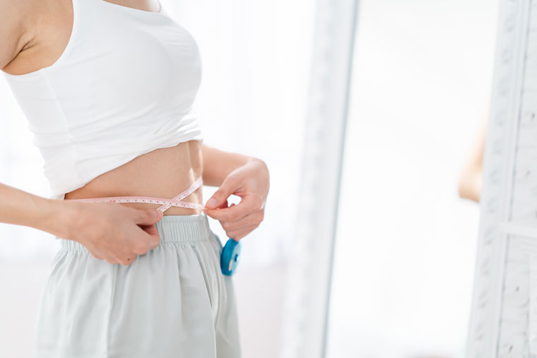 ウエストをメジャーで測る女性