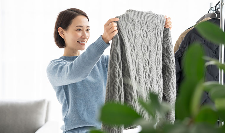 ニットの洋服を持つ女性