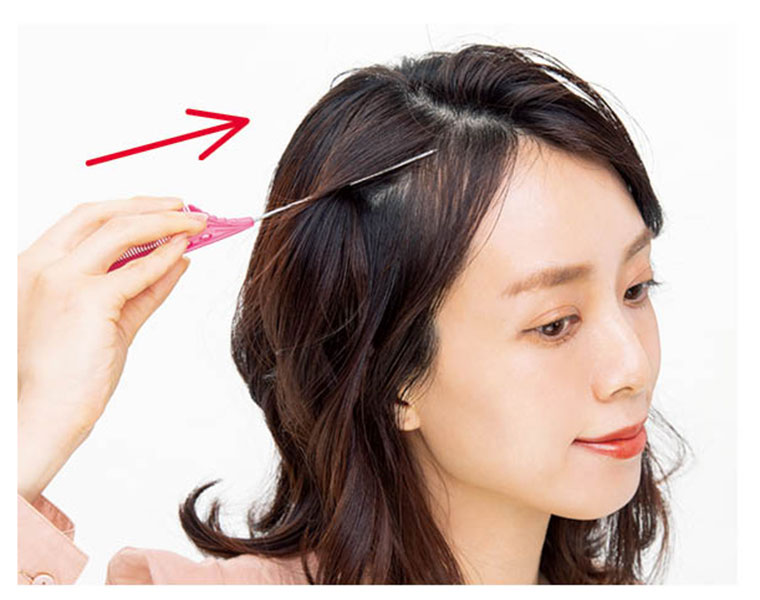 くしの柄で髪をすくう