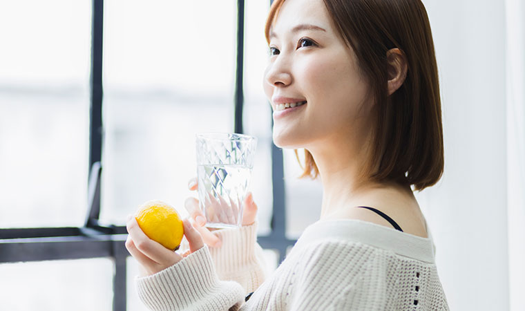 水が入ったグラスとレモンを持った女性