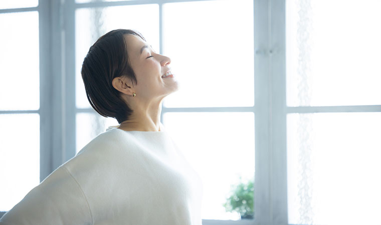 窓辺で伸びをする女性