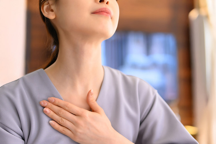 鎖骨に手をあてる女性