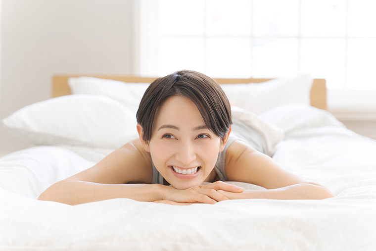 ベッドでうつ伏せになる女性